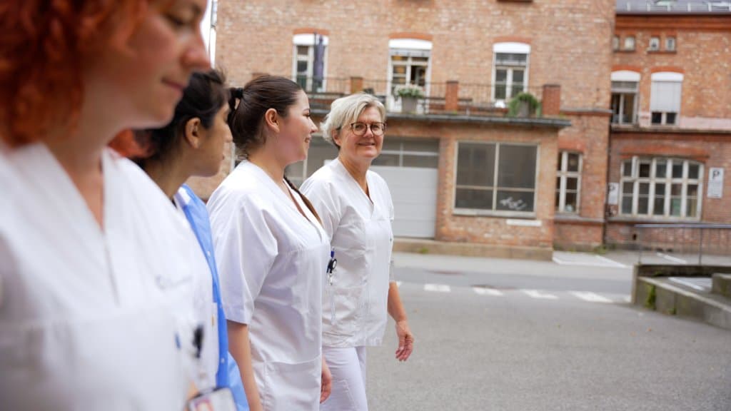 Flere personer i hvite helse-uniformer går og snakker sammen utenfor Ullevål sykehus.