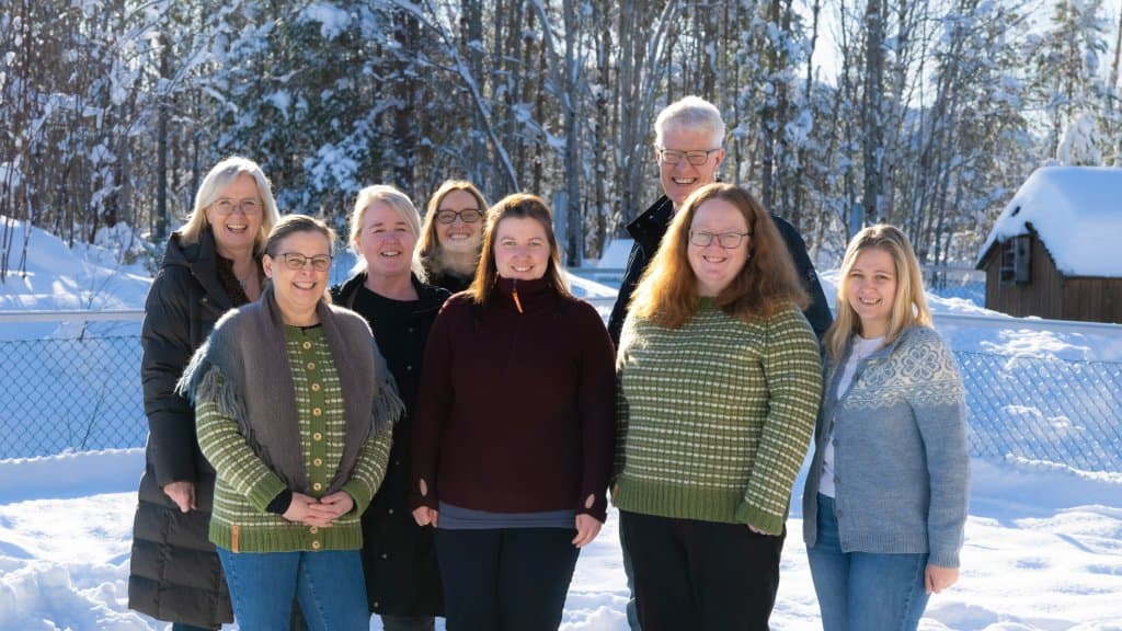 Foto av ei gruppe ansatte i Straumsnes kommune. Dei står ute i ein barnehage. Sola skiner, og dei smilar til kamera.
