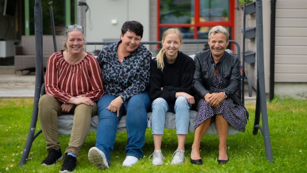 Fire damer sitter på en benk.